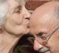 An older woman kissing the bald head of an older man