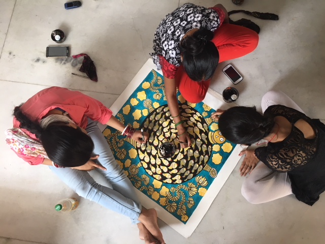 Aerial view of three artisans work together on a painting